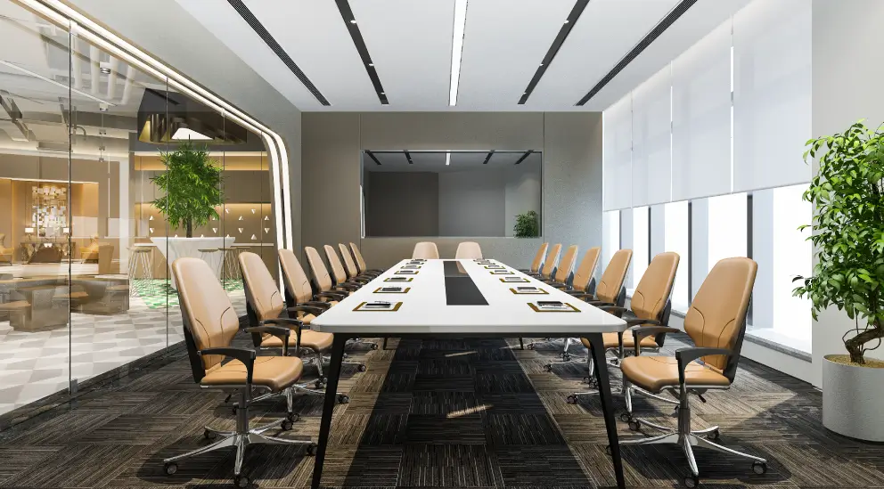 Large conference room with a long white table, tan leather chairs, and a wall-mounted display screen